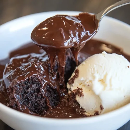 A spoonful of rich chocolate pudding cake dripping with chocolate sauce